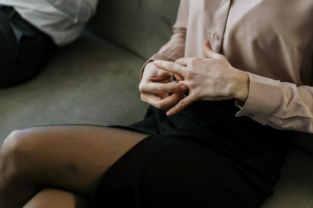 Person in White Button Up Shirt and Black Skirt Sitting on Gray Couch